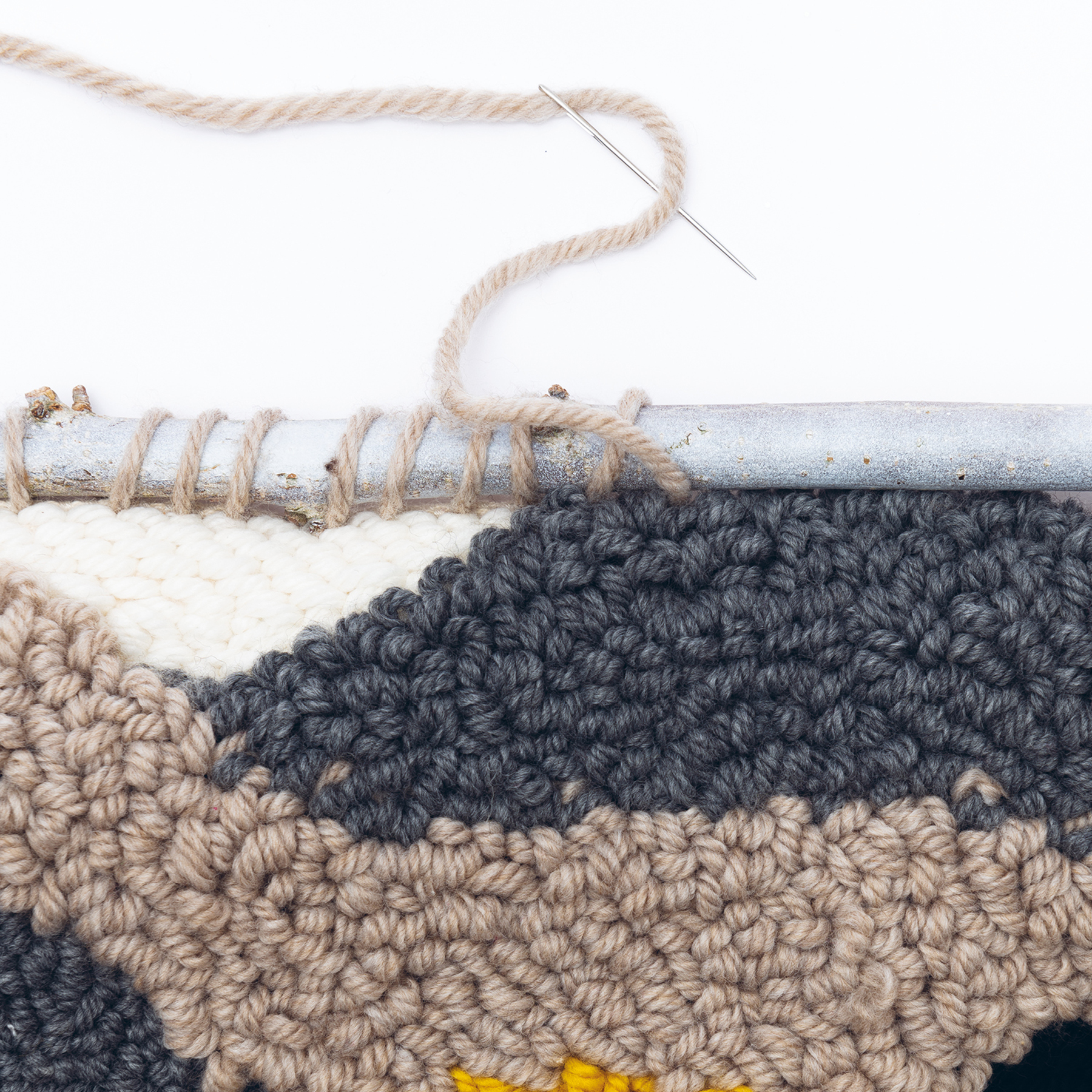 Punch Needle Modell wird mit Wollfaden an Stange genäht