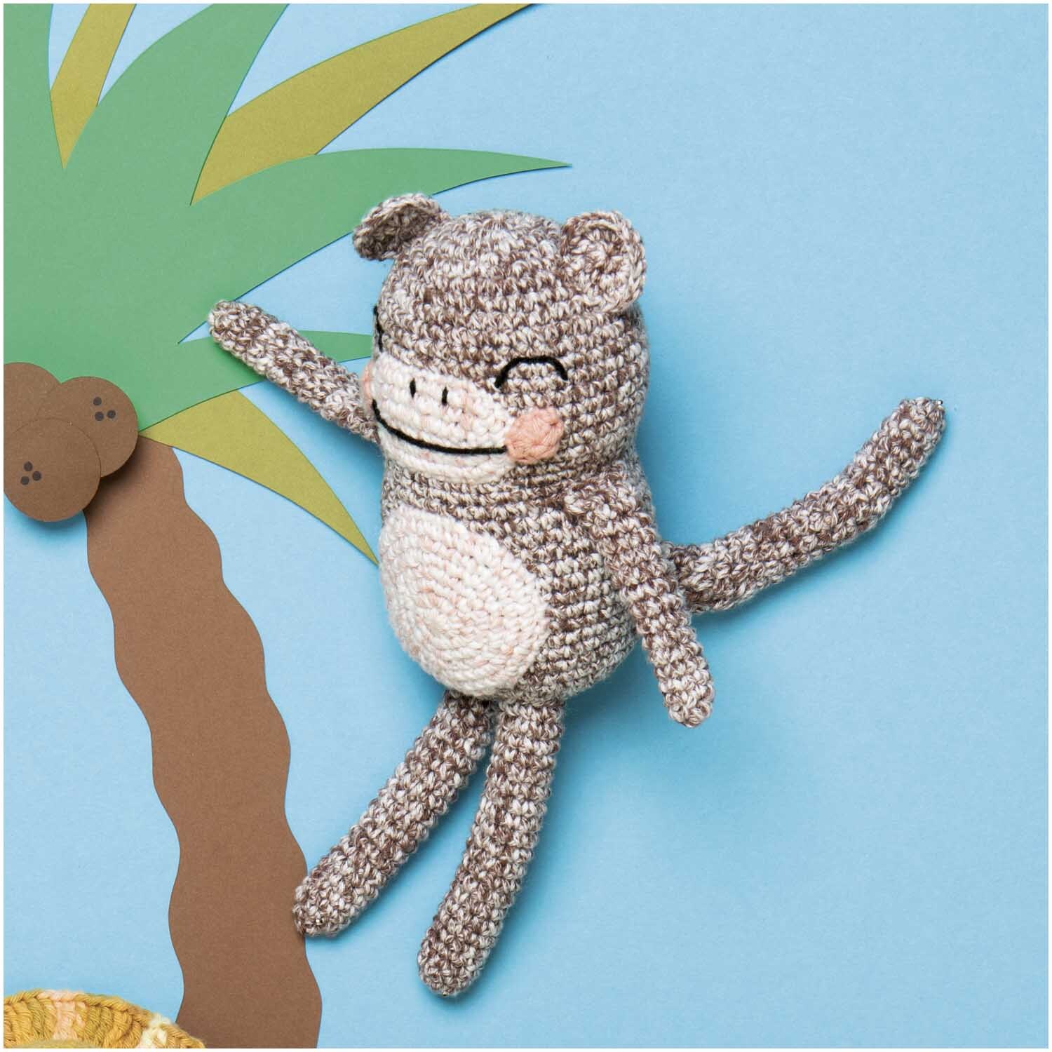 Creative Ricorumi Spray dk: Ein gehäkeltes, braunes Stofftier hängt fröhlich an einer Palme.