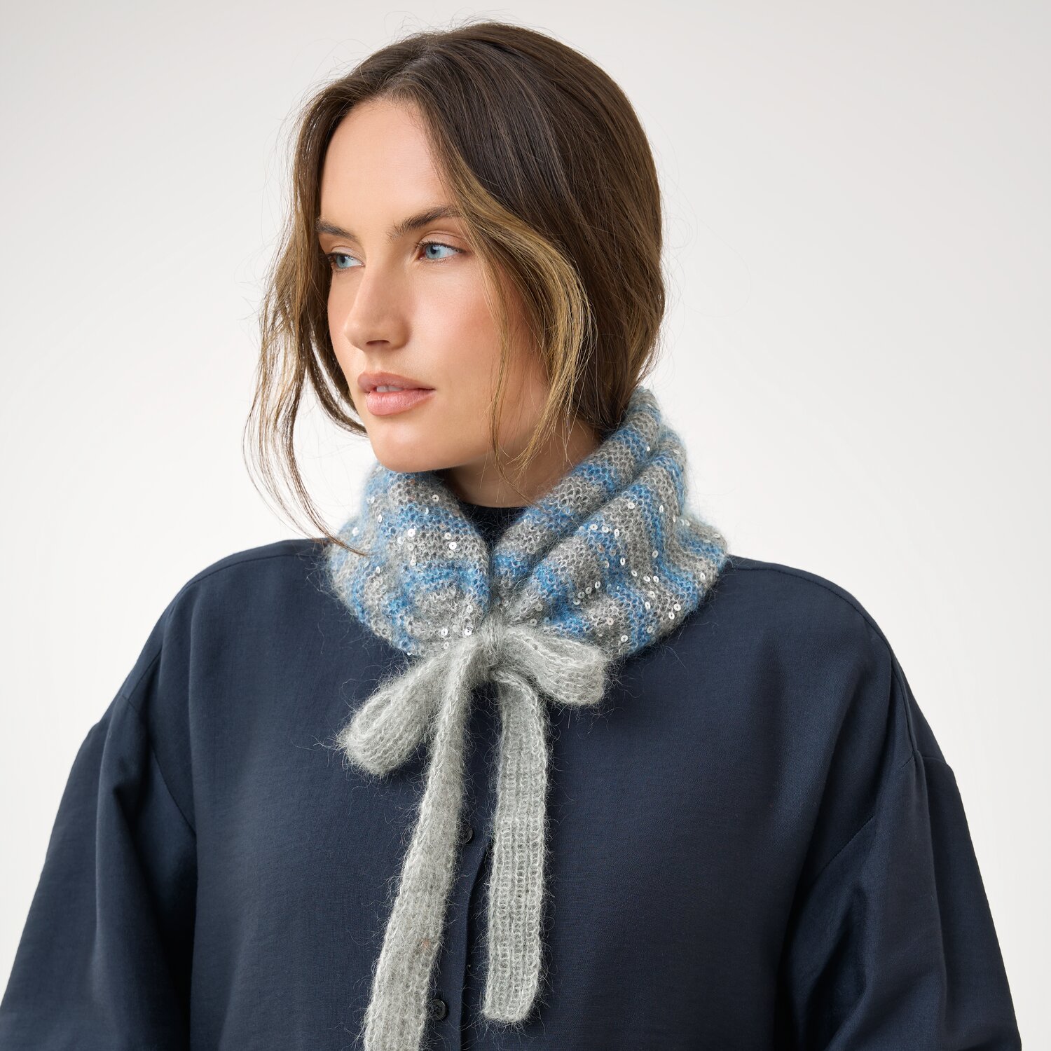 Strickset Schalkragen Modell 21b aus Die Neue Masche No. 16, gestrickter flauschiger Kragen mit Schleifenbindung in sanften Pastelltönen an Frau auf neutralem Hintergrund